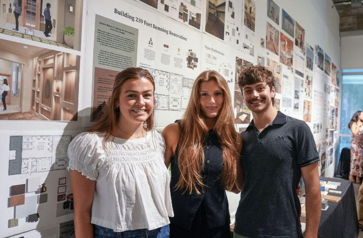 photo of three people standing in front of posters on a wall