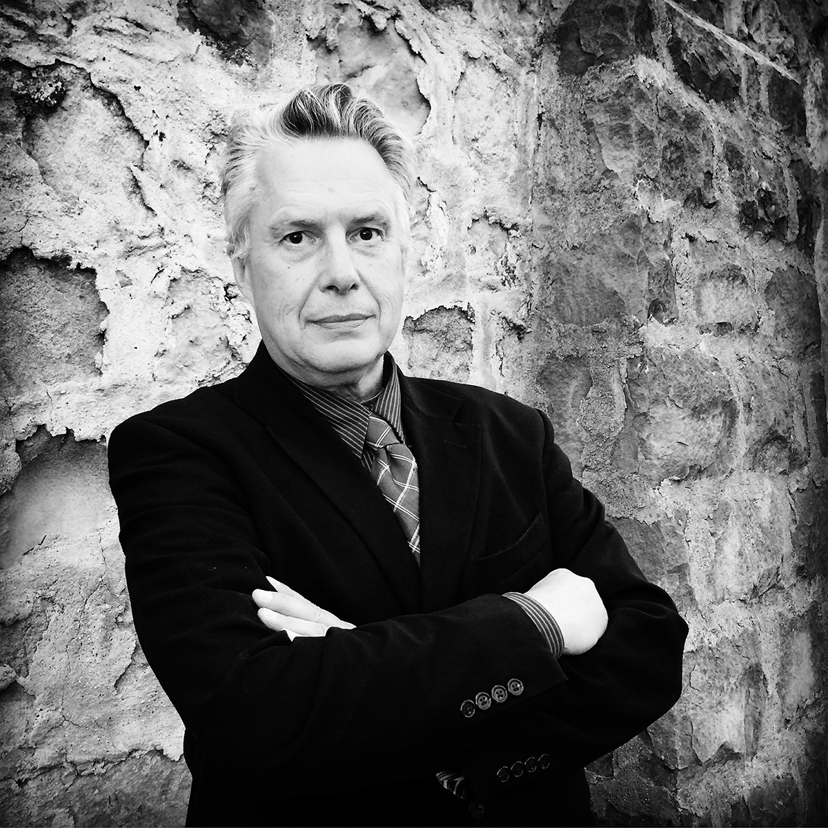 black and white photo of man, with stone wall