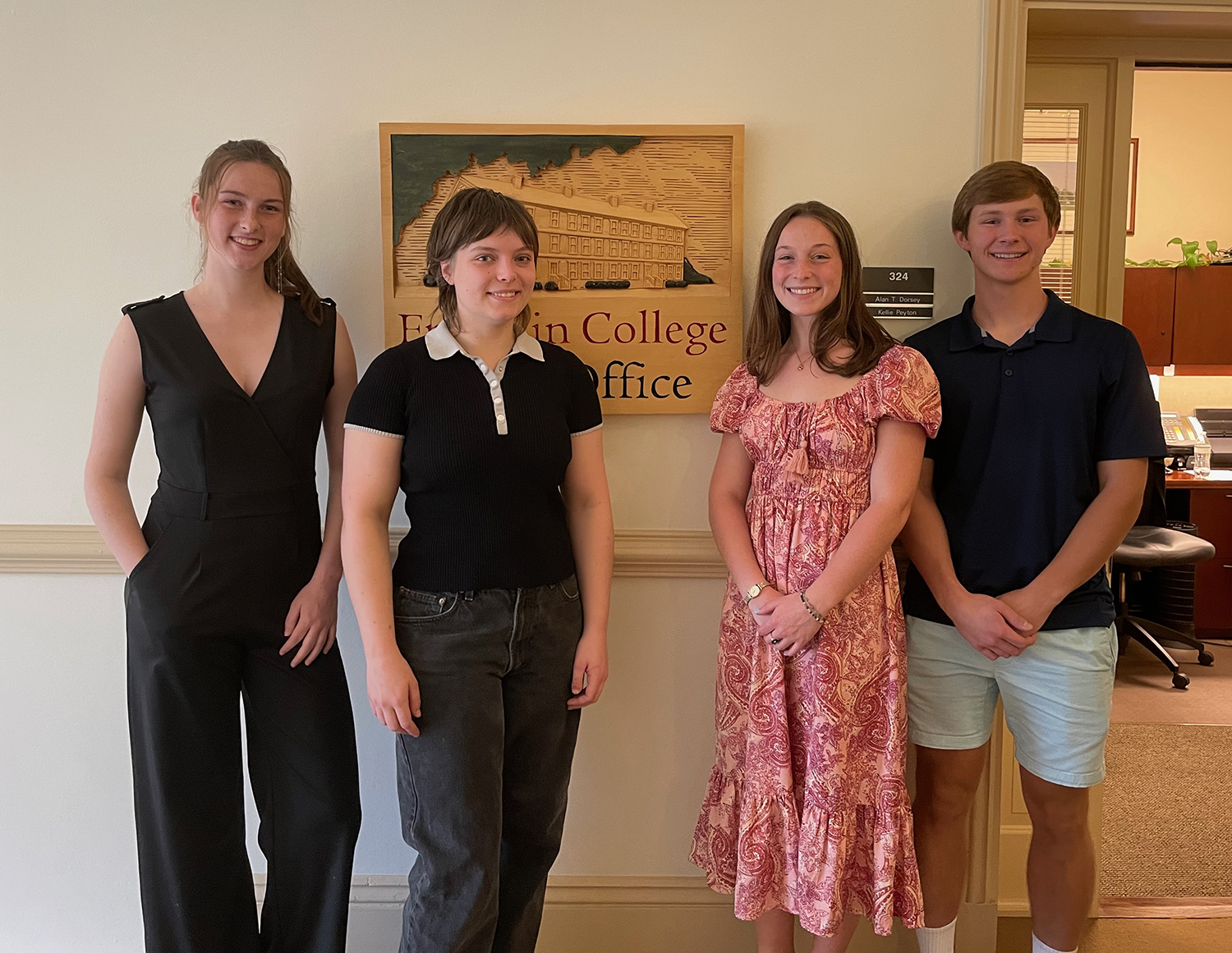 photo of three women, one man, with sign in background