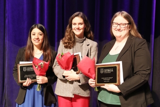 photo of three women holding plaques at ceremony