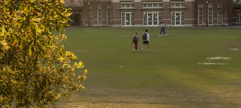 photo of students on quad near sunset, building in background