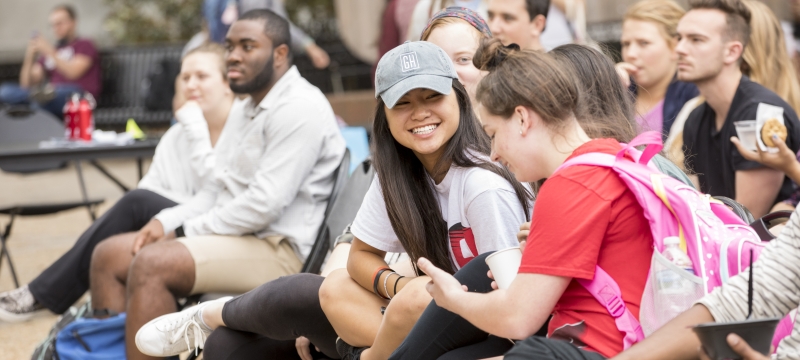 photo of seated outdoor crowd of spectators, two women in foreground