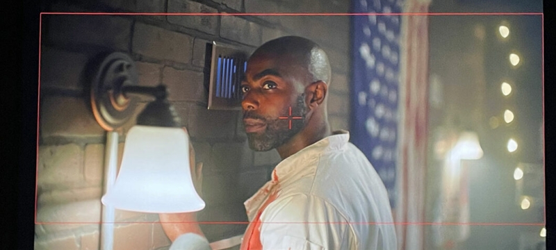 film still of man, with wall light and flag