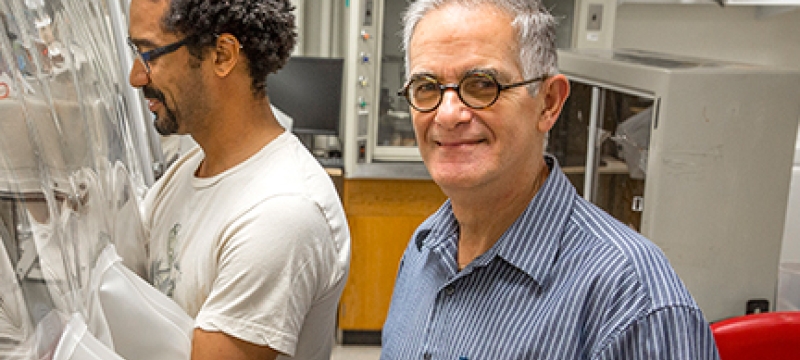 two men in a lab, one looking at camera