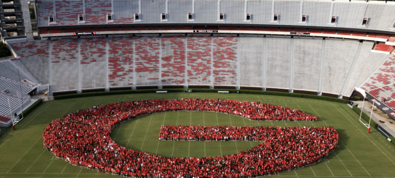 photo of letter G formed by people in stadium, day