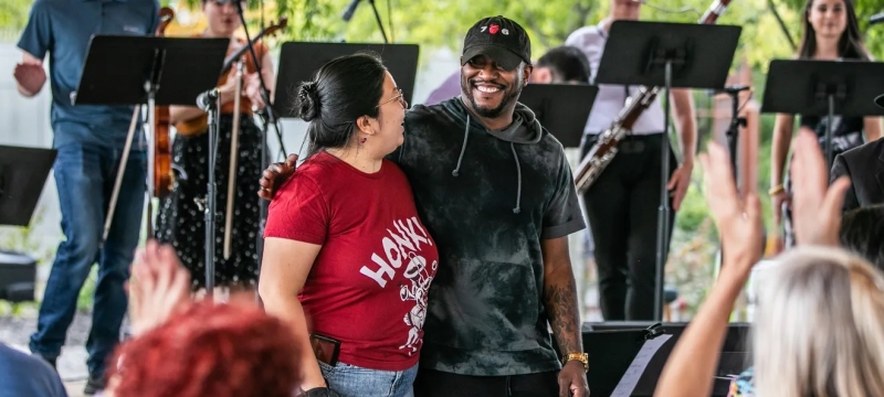 photo of musicians with instruments and music stands, two people in foreground