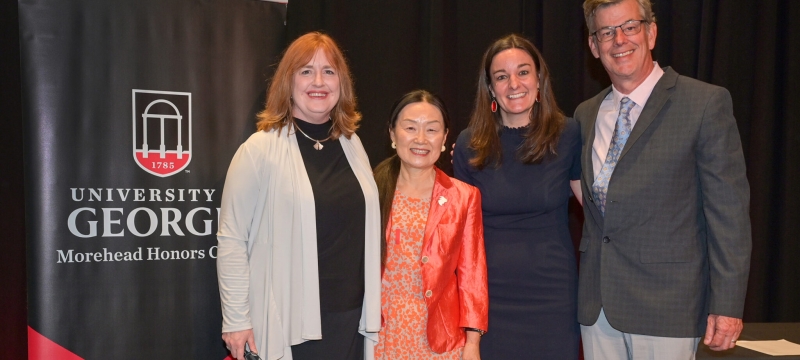 photo of four people, with banner