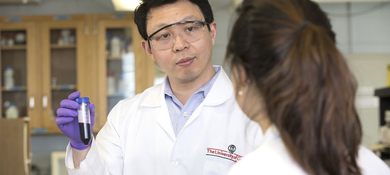 photo of two people in lab coats, foreground figure with back turned to camera