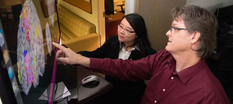 photo woman and man pointing to computer screen