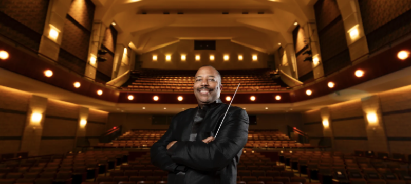 photo of man in performance hall, seats and lights in background