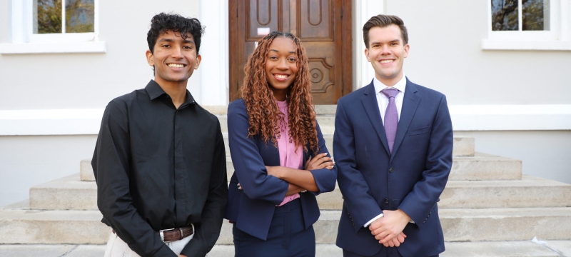 photo of three people, building in background, day