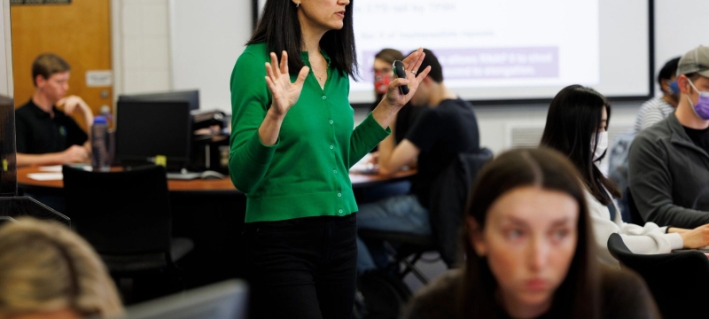 photo of woman, with students at computers
