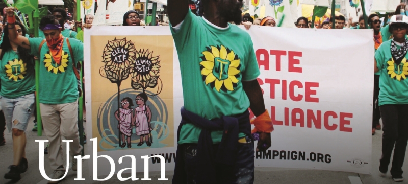 photo of man at protest, with arm raised, with signs and banners in city 