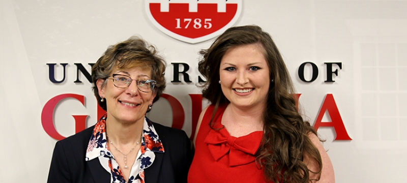 photo of two women standing in front of UGA logo