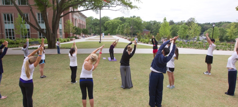photo of group of people stretching with arms overhead, outdoors