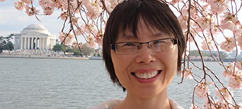 photo of woman with cherry blossom and Lincoln memorial in background