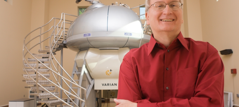 Photo of man standing in front of NMR machine