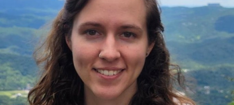 headshot photo of woman, outdoors, mountains in background