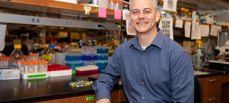 photo of man in lab, with table and lab equipment