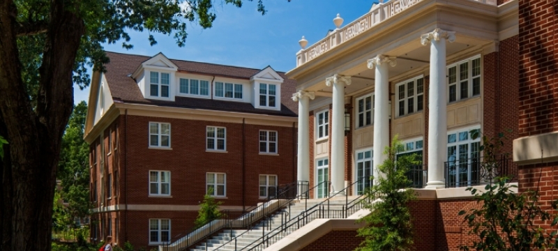 photo of building, day, blue sky, with person approaching staircase