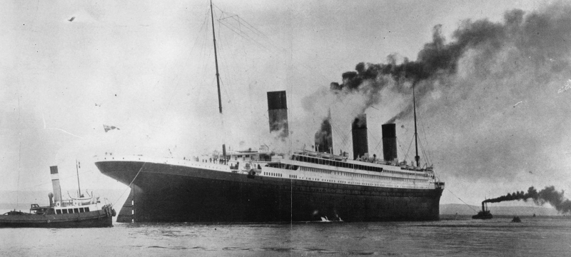 black and white photo of ship and tugs