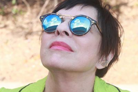 photo of woman looking up, with sunglasses reflecting sky